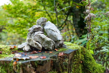 Steine geschlichtet zu einem Steinmännchen im Wald auf einem Baumstamm