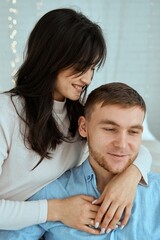 Happy girl hugging a guy in a blue shirt. Attractive couple posing together for a family photo.