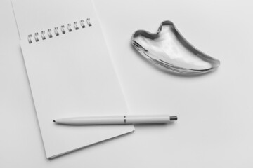 Top view of open spiral blank notebook with pen with heart-shaped gouache massage.