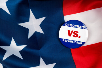 democrats vs republicans text quote on election button laying on the star spangled banner. united...