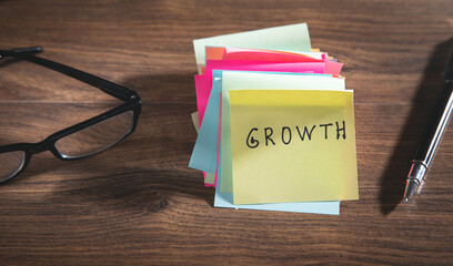 Text Growth on sticky note with a pen and eyeglasses.