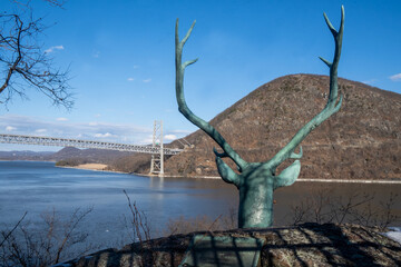 Stony Point, NY - USA - Feb 10, 2022 Horizontal view of Giacomantonio Archimedes's bronze statue, Bronze Elk Head , built in 1936, with the Bear Mt Bridge and Hudson River in the background.
