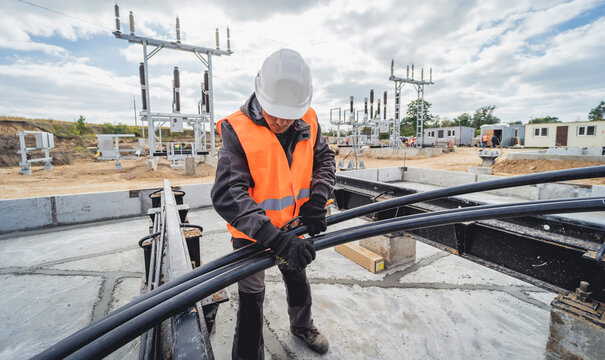 Two electrician builder workers installing high-voltage cable