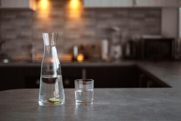 carafe with detox water and a glass on the table in the kitchen