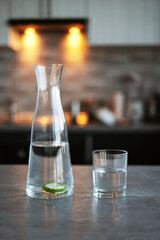 carafe with detox water and a glass on the table in the kitchen