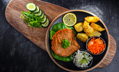 Pork cutlet coated with breadcrumbs with potatoes and salads
