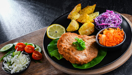 Pork cutlet coated with breadcrumbs with potatoes and salads