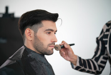 Professional actor preparation before shoot. Handsome young man applying by professional make up of visagist. Male makeup