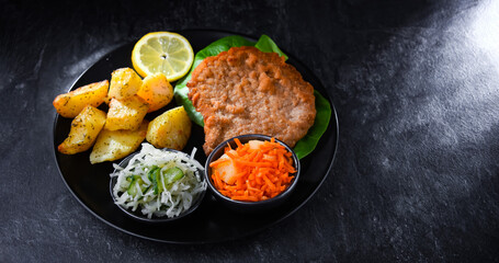 Pork cutlet coated with breadcrumbs with potatoes and salads