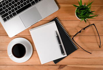 Work from home. desk office with laptop, blank notepad, coffee cup and pen on wood table