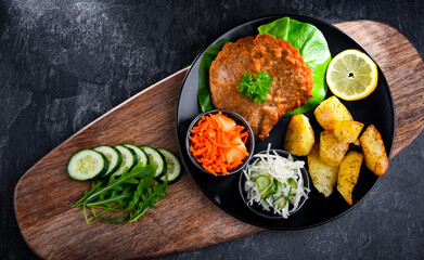 Fototapeta na wymiar Pork cutlet coated with breadcrumbs with potatoes and salads