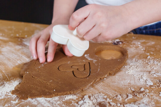 A little girl makes heart-shaped cookies from rye dough. The concept of Valentine's Day and healthy baking.