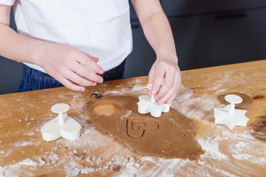 A little girl makes heart-shaped cookies from rye dough. The concept of Valentine's Day and healthy baking.