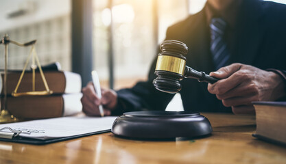 Young lawyer holding gavel and sitting at desk, legislation and justice concept.