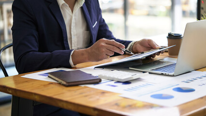 Male businessman analyzes income charts and business graphs and strategy ideas, hand holding pen pointing financial paper charts..