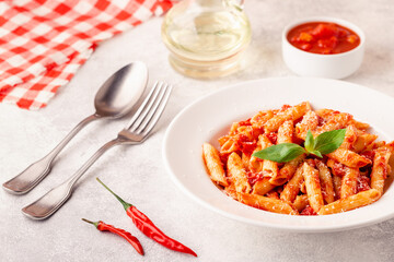 Classic italian pasta penne alla arrabiata with fresh basil on a light background