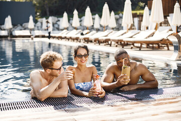Three friends in a swimwears relaxing near swimming pool