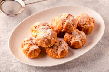 Homemade profiteroles with powdered sugar.