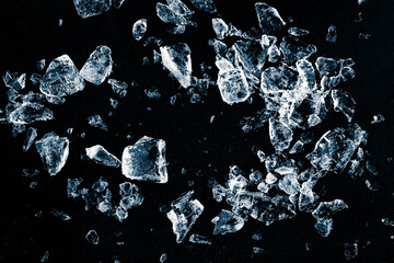 Pieces of crushed ice cubes on black background. Ice debris pattern.