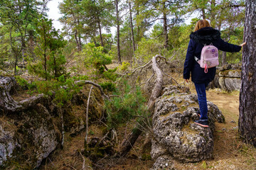 Obraz premium Woman climbing a rock in the forest of the Enchanted City of Cuenca, Spain.