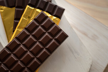 Chocolate bars with open gold cover. Stack of chocolate bars. Flat lay composition with delicious chocolate isolated on white background. Space for text