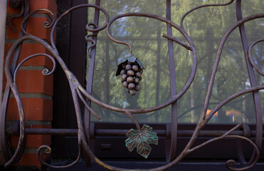 Exquisite forged decorative elements of a metal fence. Modern facades of fences with forged grape fruits and leaves