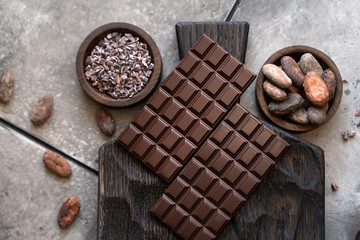 Stack of chocolate bars with cocoa beans. Flat lay composition with delicious chocolate on black...