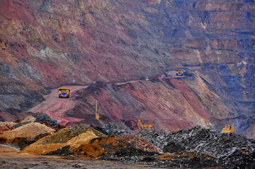 Extraction of iron ore. A mining dump truck transports iron ore along a side carrea. Special equipment works in a quarry. Overall plan.  © Yevhen