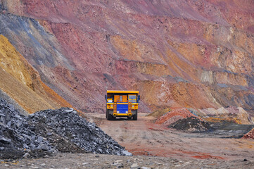 Extraction of iron ore. A mining dump truck transports iron ore along a side carrea. Special equipment works in a quarry © Yevhen