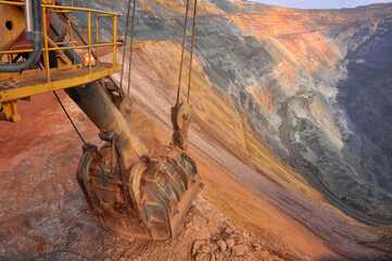 excavator bucket lies on the edge of the side of the iron ore quarry. Quarry panorama
