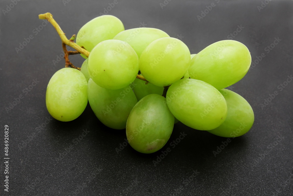 Wall mural fresh green grapes bunch closeup in black background