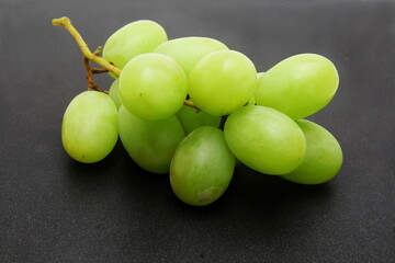 fresh green grapes bunch closeup in black background