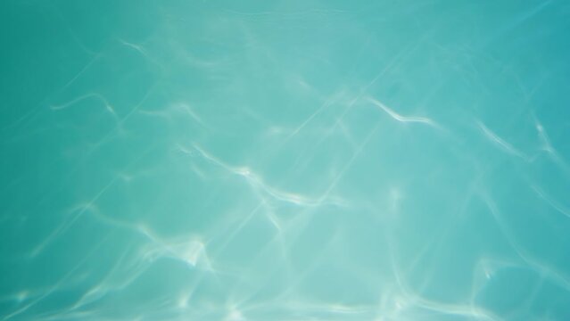 Underwater shot of blue water column with sparkling and moving light reflections. Transparent water with glare sparkles in rays of light. Real sea or ocean water, pool. Close up in slow motion.