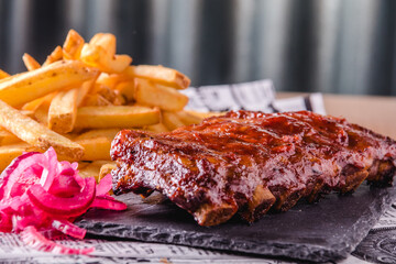 Close up view of grilled BBQ ribs with french fries served and ready to eat
