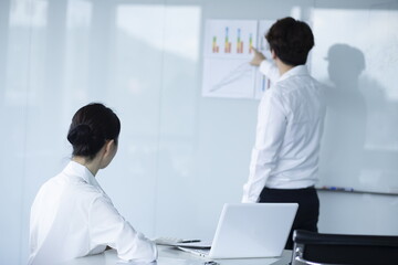 Businessman Explaining and Pointing at Chart on Board