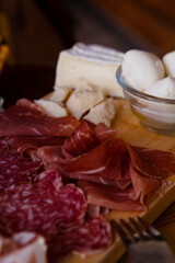 Cheese and meat board in an Italian restaurant in Cremona, Lombardy, Italy with mozzarella, prosciutto, salami, ham, brie, parmesan, bread sticks. Italian food in Europe. European antipasti and snacks