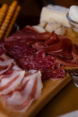 Cheese and meat board in an Italian restaurant in Cremona, Lombardy, Italy with mozzarella, prosciutto, salami, ham, brie, parmesan, bread sticks. Italian food in Europe. European antipasti and snacks