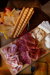Cheese and meat board in an Italian restaurant in Cremona, Lombardy, Italy with mozzarella, prosciutto, salami, ham, brie, parmesan, bread sticks. Italian food in Europe. European antipasti and snacks