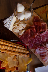 Cheese and meat board in an Italian restaurant in Cremona, Lombardy, Italy with mozzarella, prosciutto, salami, ham, brie, parmesan, bread sticks. Italian food in Europe. European antipasti and snacks