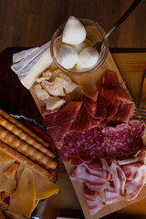Cheese and meat board in an Italian restaurant in Cremona, Lombardy, Italy with mozzarella, prosciutto, salami, ham, brie, parmesan, bread sticks. Italian food in Europe. European antipasti and snacks