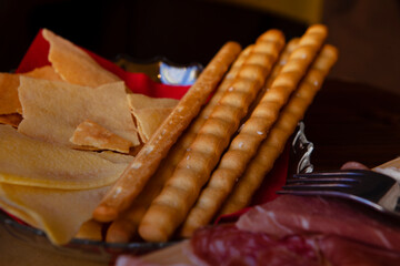 Cheese and meat board with bread sticks in an Italian restaurant in Cremona, Lombardy, Italy with mozzarella, prosciutto, salami, ham. Italian food in Europe. European antipasti and snacks