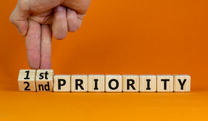 1st or 2nd priority symbol. Businessman turns wooden cubes and changes words 2nd priority to 1st priority. Beautiful orange background. Business, 1st first or 2nd second priority concept. Copy space. - obrazy, fototapety, plakaty