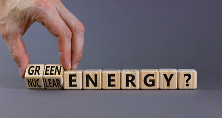 Nuclear or green energy symbol. Businessman turns wooden cubes and changes concept words nuclear energy to green energy. Beautiful grey background copy space. Business nuclear green energy concept.