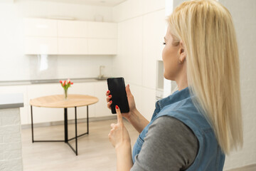 Naklejka premium Mobile Phone With Home Control System On A screen. Smart house, home automation, device with app icons. Woman uses her smartphone with smarthome security app to unlock the door of her house