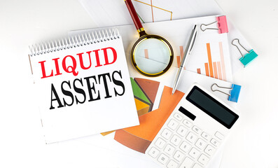 White notepad text LIQUID ASSETS with diagram,chart,calculator on the white background