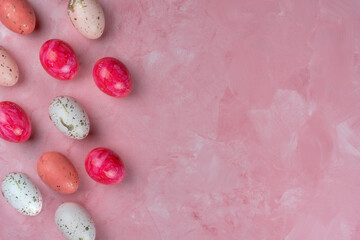 Colored easter eggs on a pink background, top view, copy space