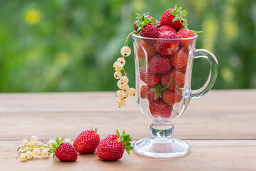 Ripe juicy strawberries and white currants in a glass bowl. Healthy food rich in fiber, vitamins,...