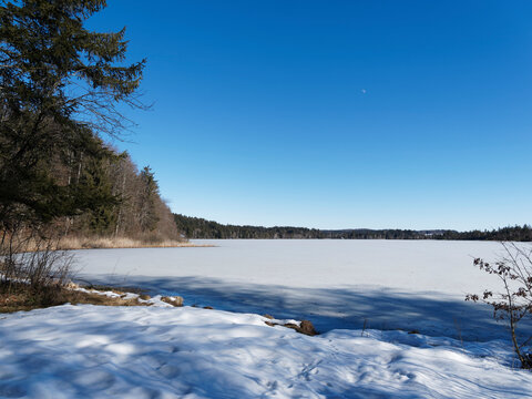 Schnee- und Eislandschaft in Oberbayern. Zugefrorener Kirchsee, kleiner Moorsee bei Sachsenkam umgeben von Buchen- und Tannenw&auml;ldern des Naturschutzgebietes bei Ellbach-Kirchseemoor