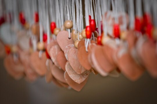 Dozens of hanging Valentine’s pendants, heart-shaped and made of wood, with tiny pearl; choose your one.