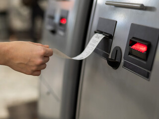 A woman takes a printed check from an ATM. 